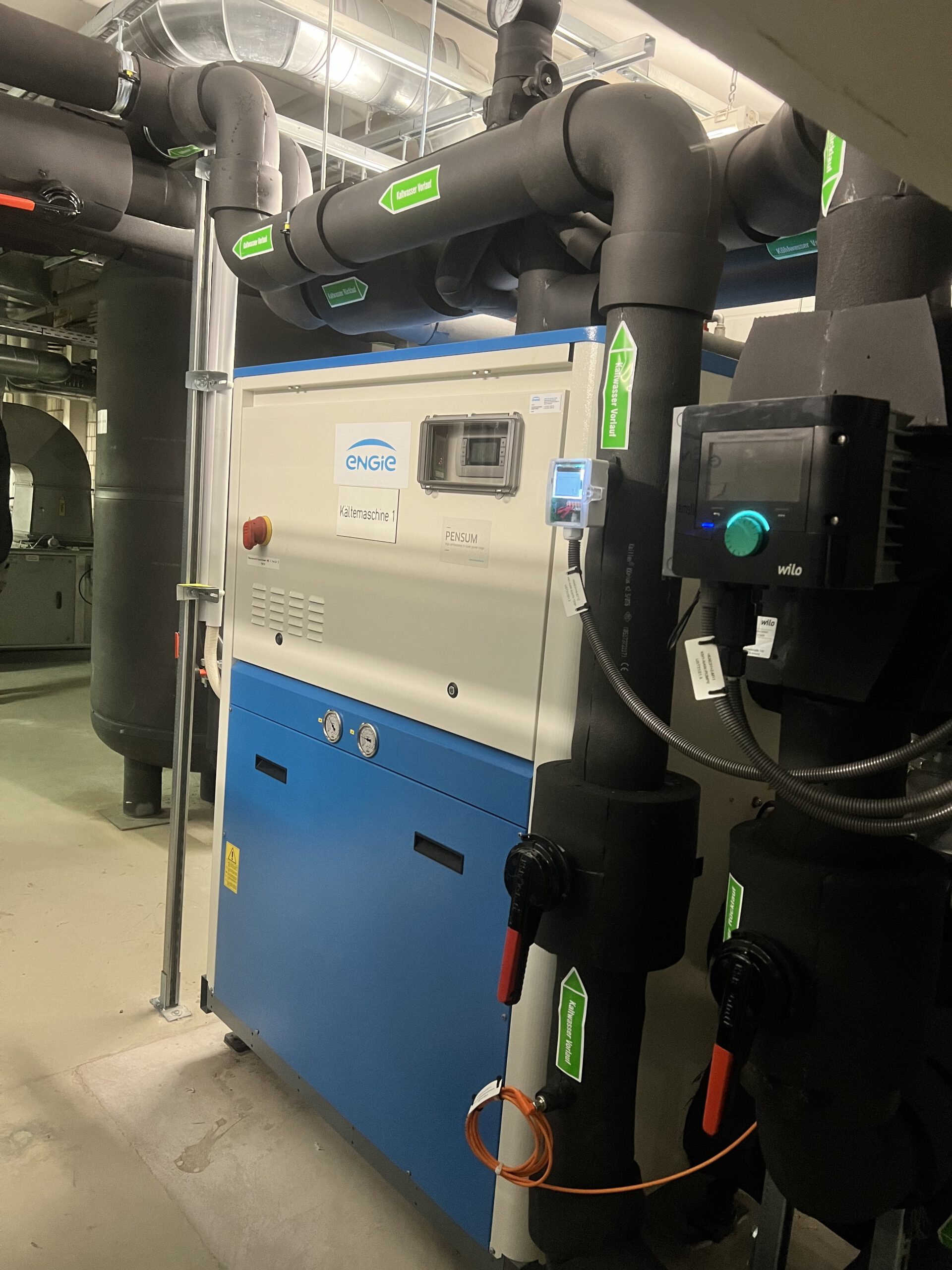 Kaltwasser Maschine Kaltwassermaschine mit angeschlossenen Rohrleitungen im Technikraum.